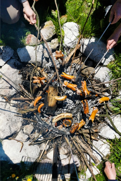 gathering around a fire, grilling hot dogs